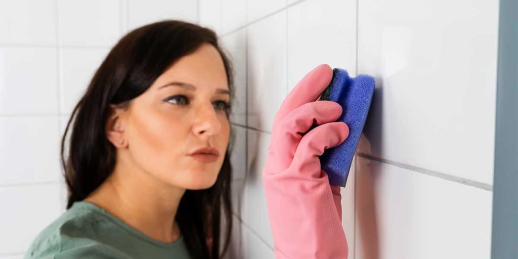 woman cleaning shower tile grout