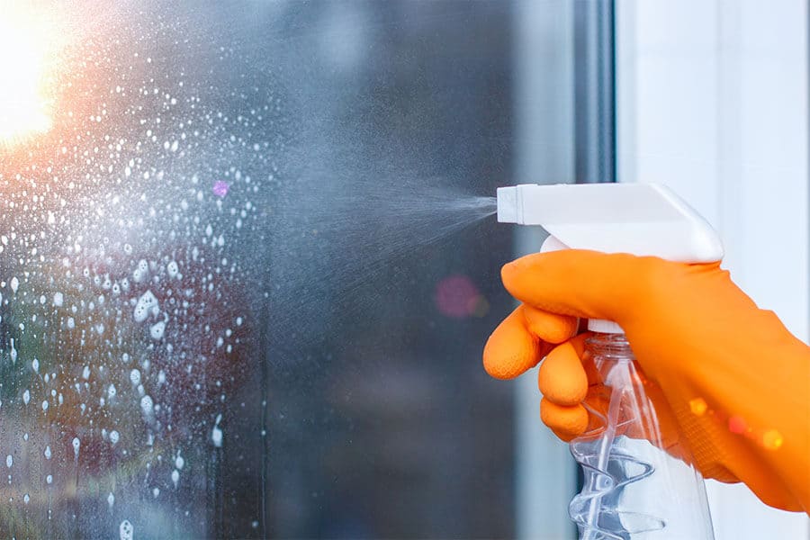 spraying glass cleaner on shower door glass