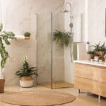 corner frameless glass shower enclosure in a modern bathroom with marble walls and wood cabinetry